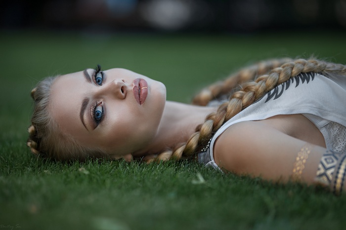Woman with blonde braids lying on grass