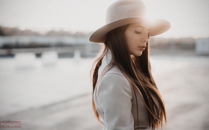 Woman in hat and white coat with closed eyes