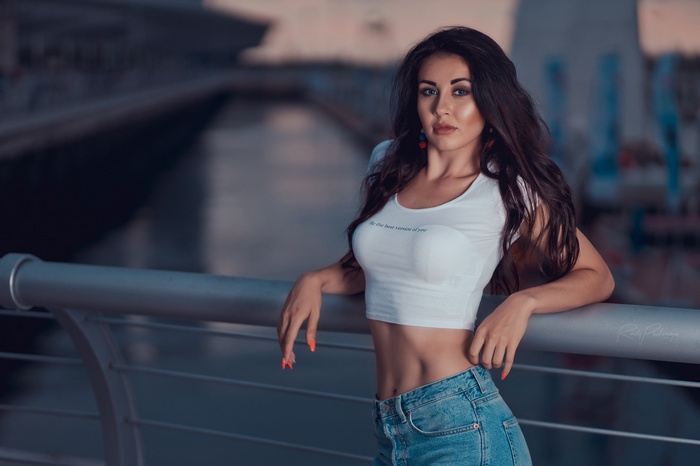 Woman in crop top and jeans leaning on railing