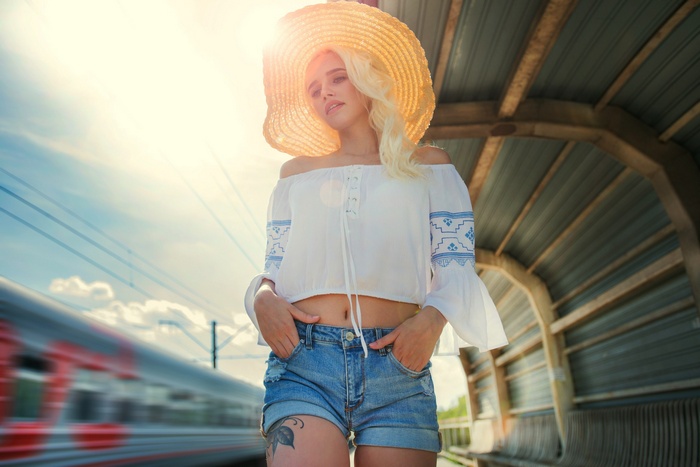 Woman in straw hat and jean shorts at train station