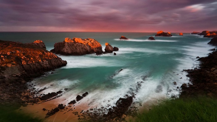 Ocean waves crash against rocky shore at sunset