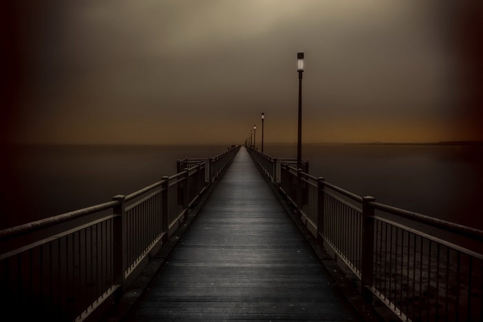 Pier with lanterns over the sea at dusk