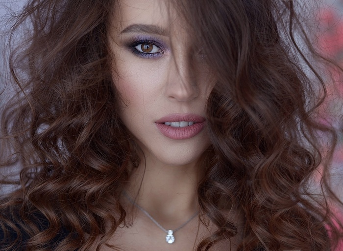 Woman with curly brown hair and makeup