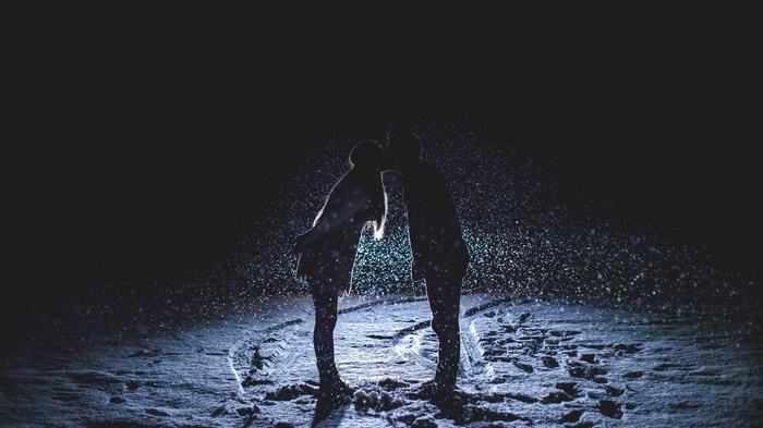 Couple kissing in the snow at night