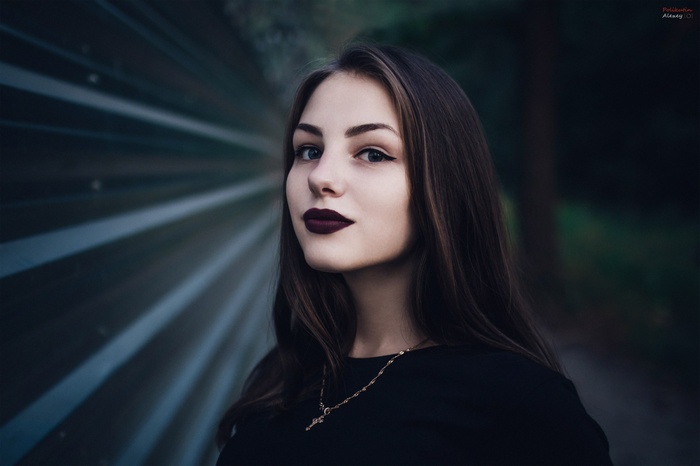 Woman with dark lipstick and necklace outdoors