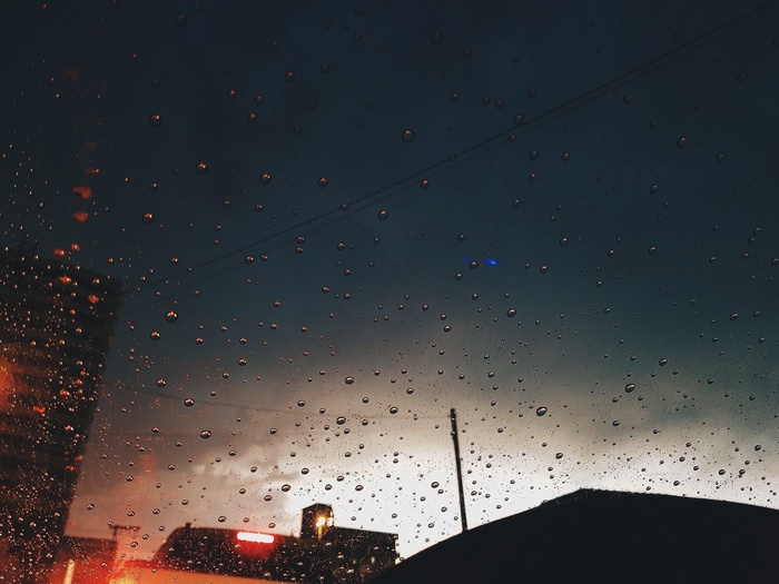 Raindrops on a window overlooking a city at dusk