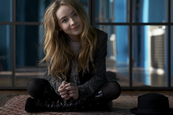 Sabrina Carpenter sitting on a rug