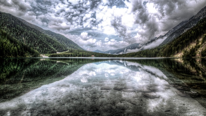 Lake reflection with mountains and forest under overcast sky