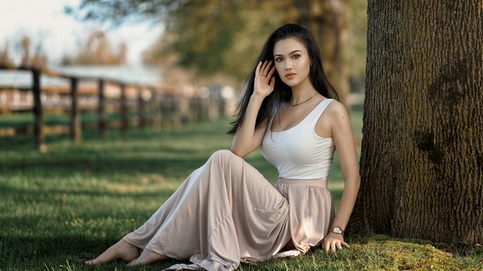 Woman sitting in grass near a tree