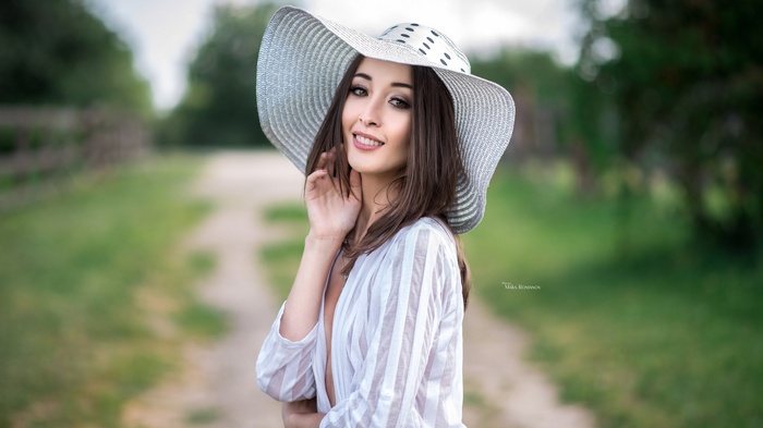 Woman in a wide-brimmed hat smiling outdoors