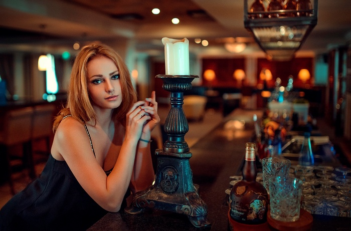 Woman at a bar with a candle and bottles