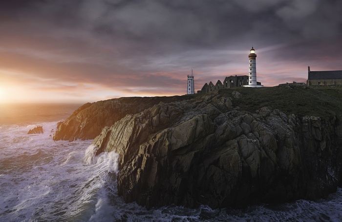 Lighthouse and ruins on a rocky coast at sunset