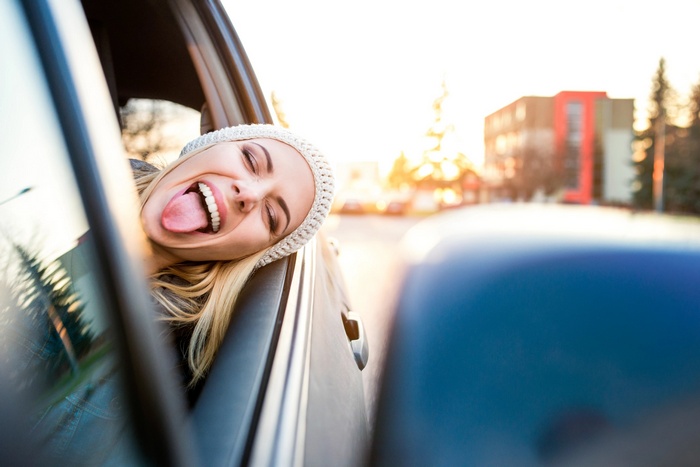 Woman sticking her tongue out of a car window
