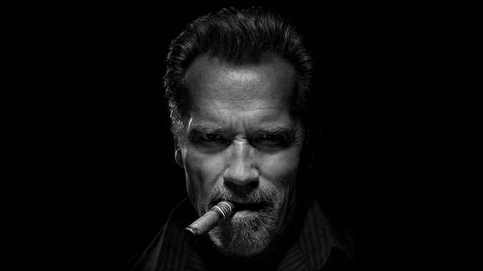 Arnold Schwarzenegger smoking a cigar, monochrome portrait