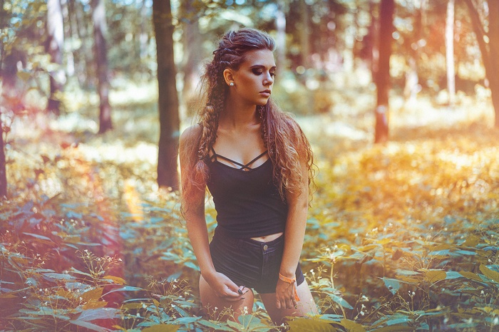 Woman with braids in black top and jean shorts in forest