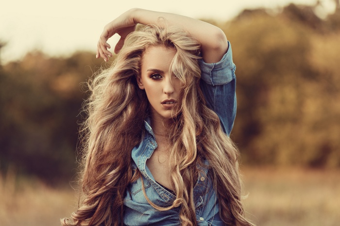Woman with long blonde hair in a denim shirt outdoors