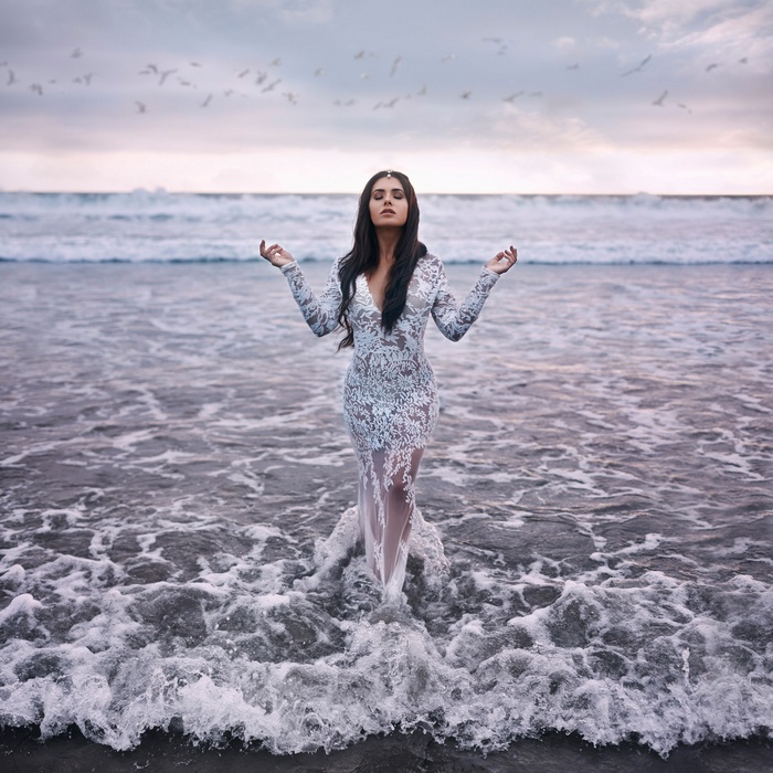 Woman in a white lace dress standing in the ocean