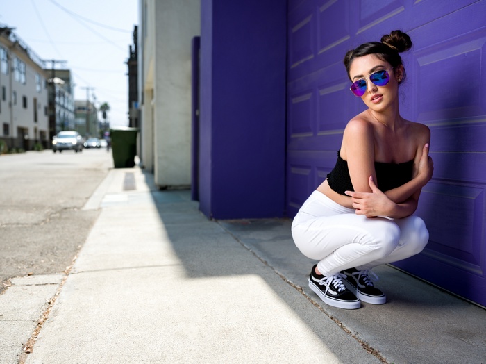 Woman in sunglasses squatting by purple garage door