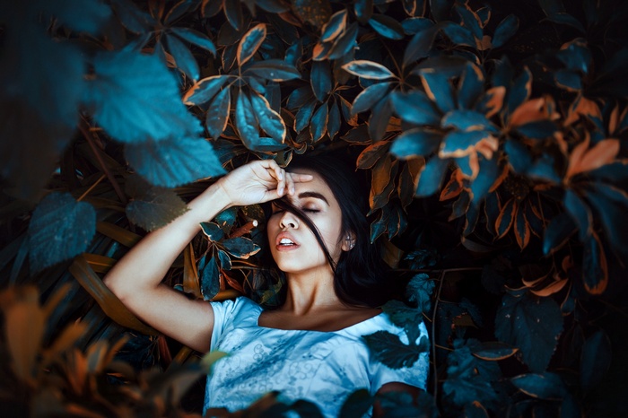 Woman lying in leaves with eyes closed