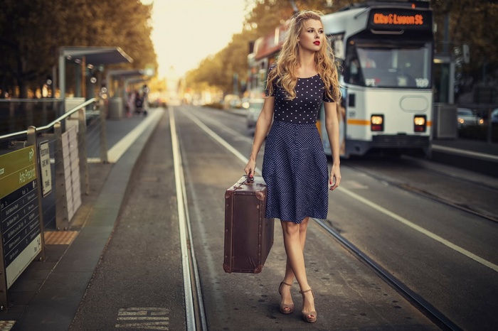 Woman with suitcase at tram stop