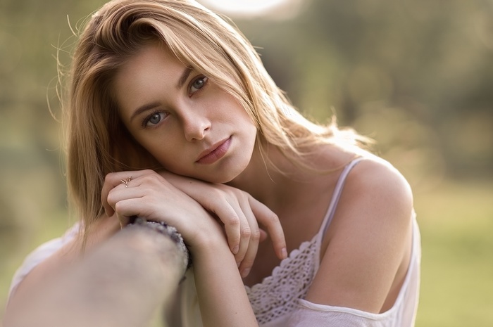 Woman with blonde hair leaning on a fence