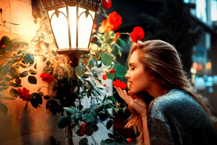 Woman smelling red roses near a lantern