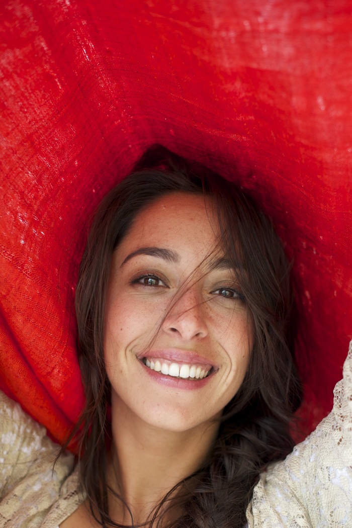 Oona Chaplin smiling under red fabric
