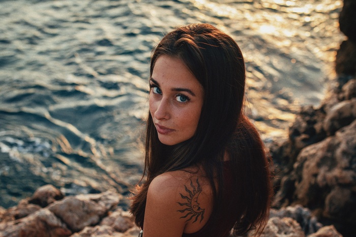 Woman with blue eyes and sun tattoo looking at viewer
