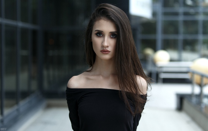 Woman with dark hair wearing a black off-the-shoulder top