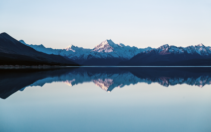 Snow-capped mountains reflected in a calm lake at sunrise