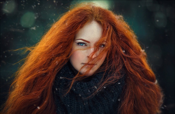 Woman with long red hair and blue eyes in the snow