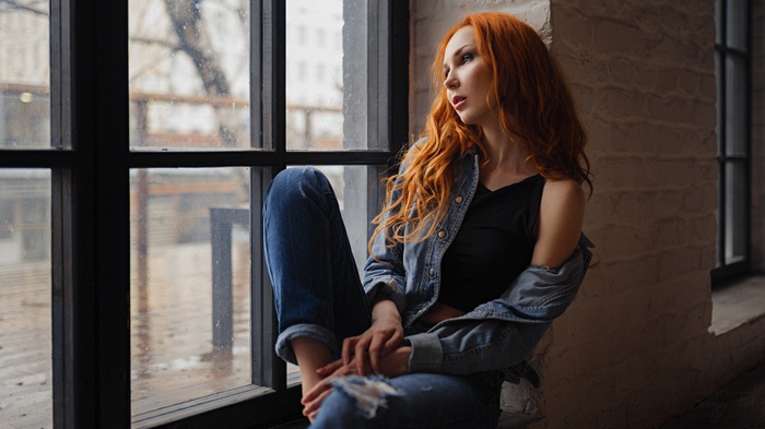 Redhead woman sitting by a window