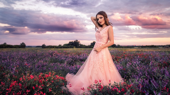 Woman in a pink dress in a field of flowers at sunset