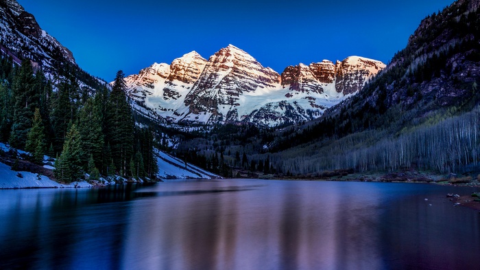Snow-capped mountains reflected in a lake at sunrise