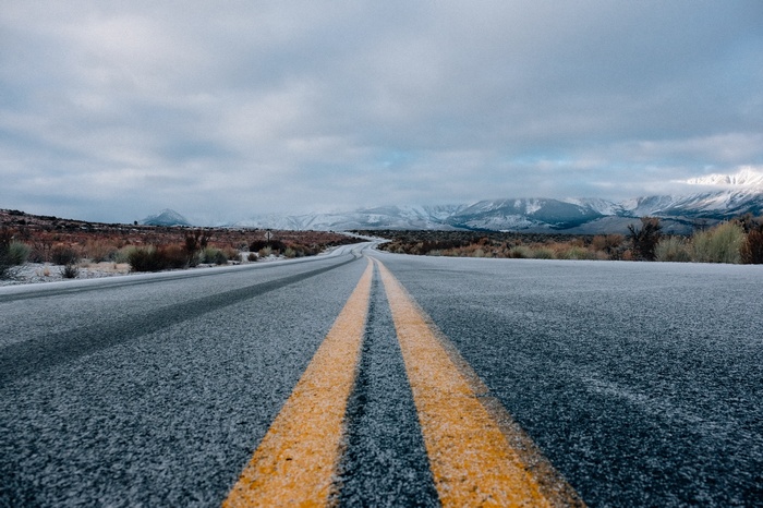 Empty road with yellow lines in a snowy landscape