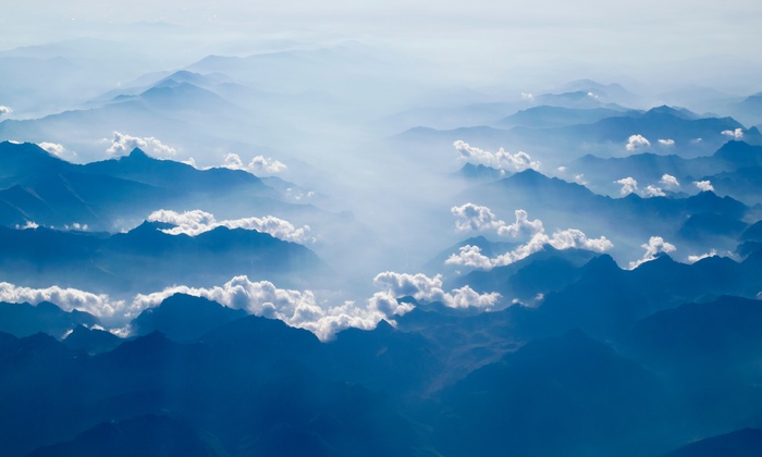 Aerial view of misty blue mountains and clouds