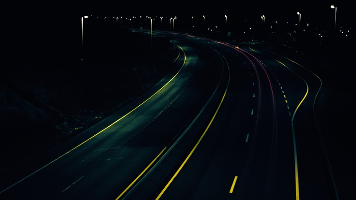 Night highway with streetlights and car light trails