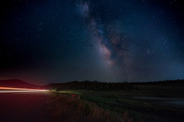 Milky Way over a road with light trails at night