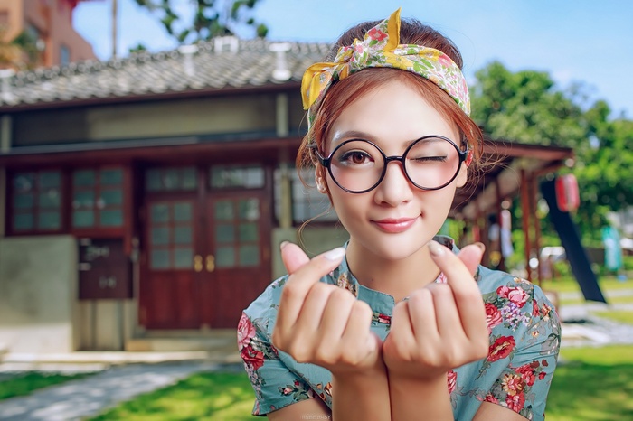 Woman with glasses and floral shirt making heart sign