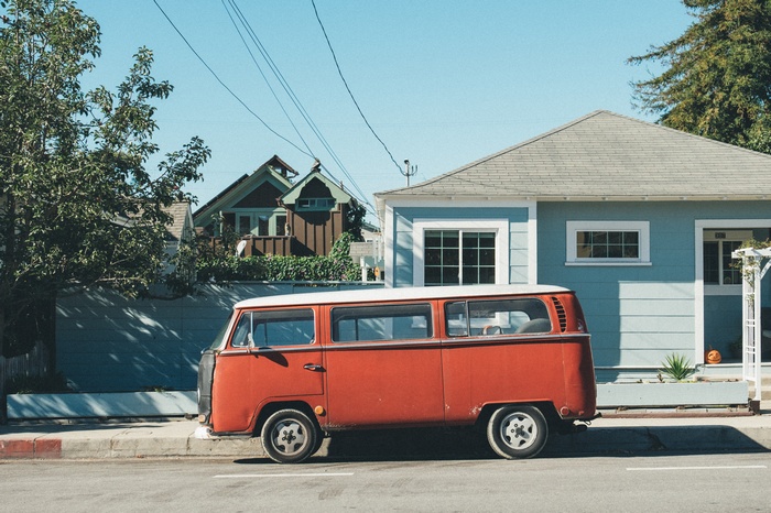 Red Volkswagen van parked on a street in front of houses