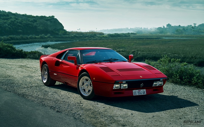 Red Ferrari 288 GTO on a dirt road near a marsh