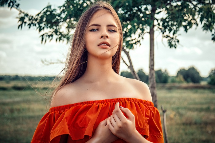 Young woman with blue eyes in an orange dress outdoors