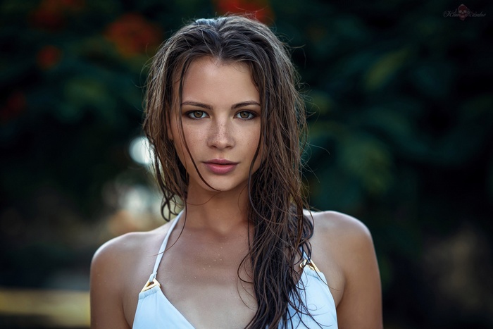 Woman with wet hair and freckles in a white bikini