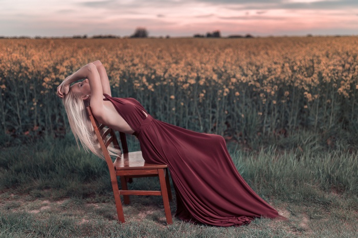Woman in a maroon dress sitting on a chair in a field