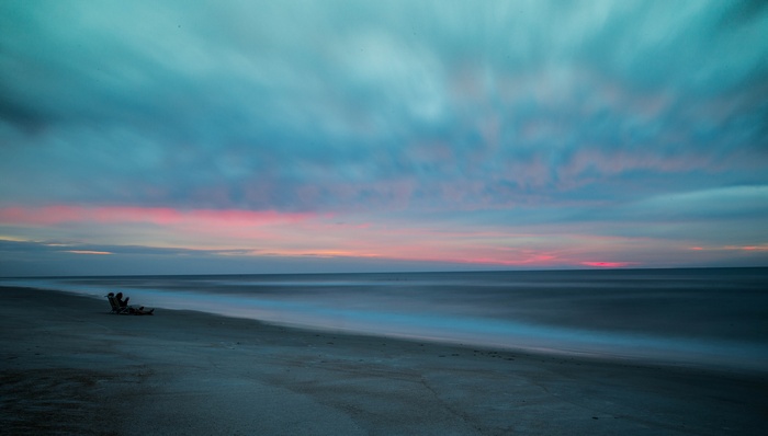 Person sitting on a beach chair at sunset