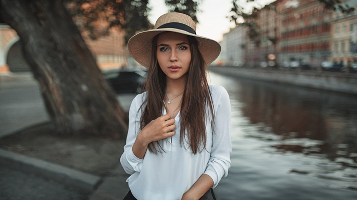 Woman wearing a hat and white shirt by a canal