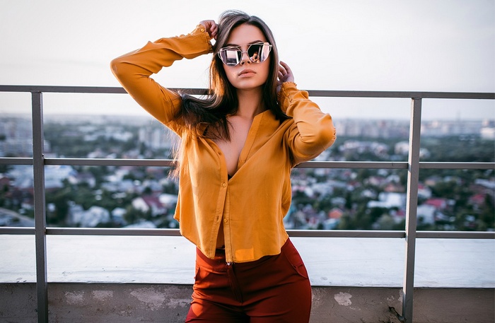 Woman wearing sunglasses and yellow shirt on rooftop