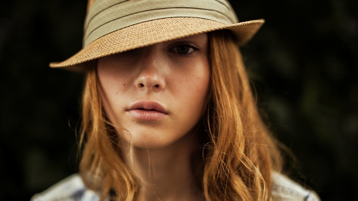 Young woman with red hair wearing a straw hat