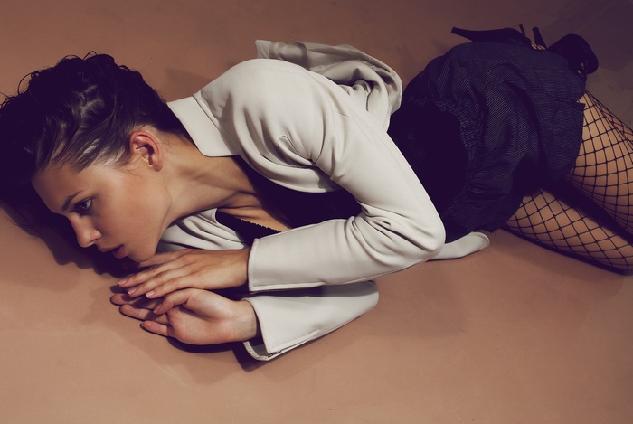 Woman in white jacket and fishnet stockings lying down