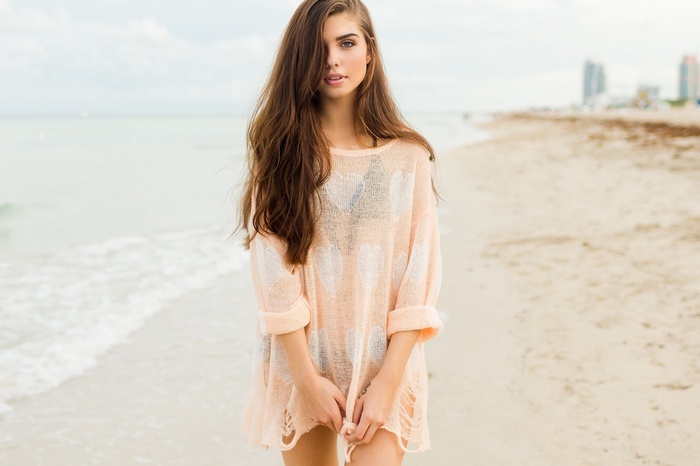 Woman in a sheer sweater on a beach
